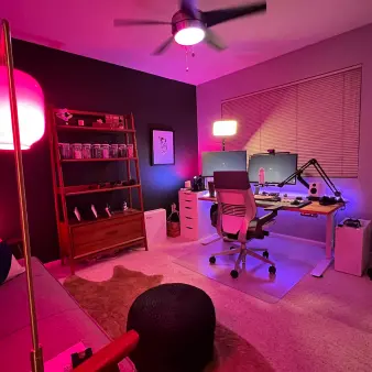 A room set-up with a desk, monitors, and microphone. 