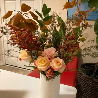 A bouquet of roses and autumn leaves in a vase. 
