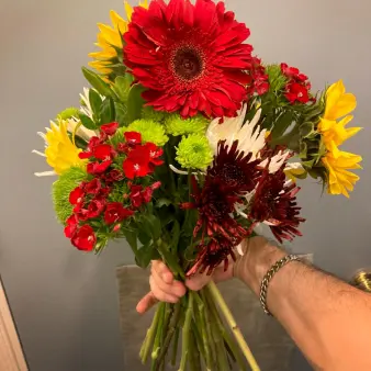 A hand holding a bouquet of multicolored flowers.