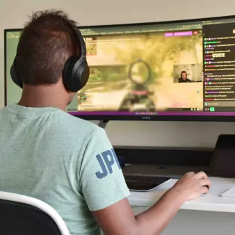 A user playing videogames on a monitor screen seen from behind.